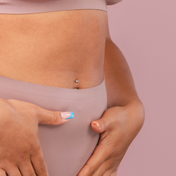 Vrouw in roze kleding houdt haar vast, symboliseert endometriose pijn
